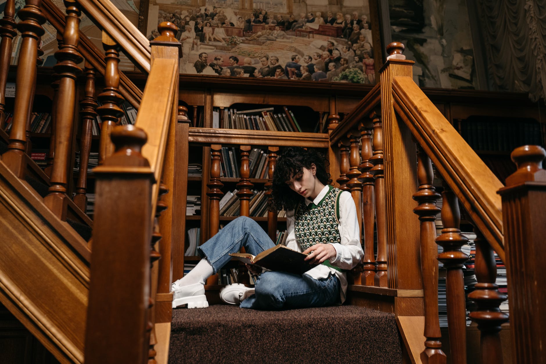 a college student reading a book white sitting on the stairs